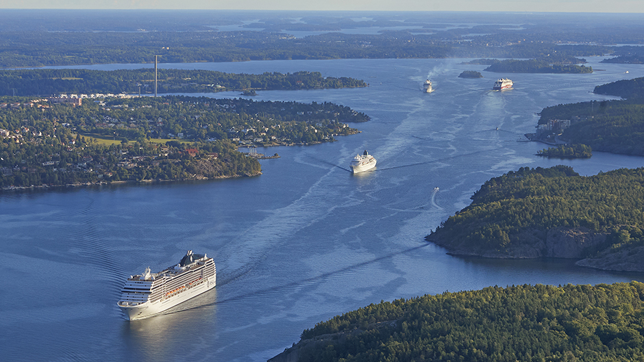 Flygbild över farleden in till Stockholm där flera stora fartyg är på väg ut och in.