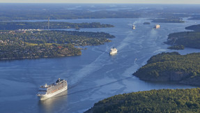 Flygbild över farleden in till Stockholm där flera stora fartyg är på väg ut och in.