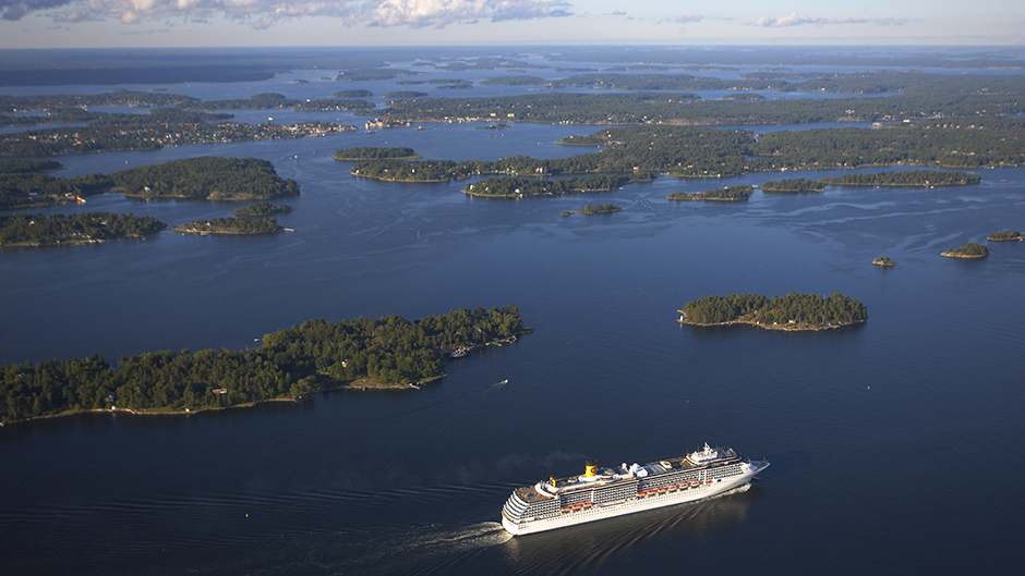 Flygbild över ett kryssningsfartyg som stävar genom Stockholms skärgård