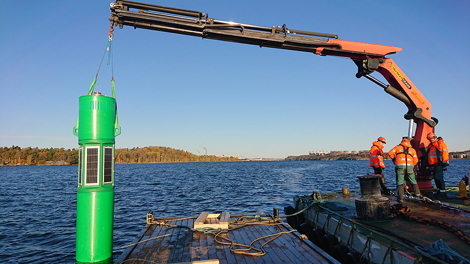 Crane lifts green bouy into the water