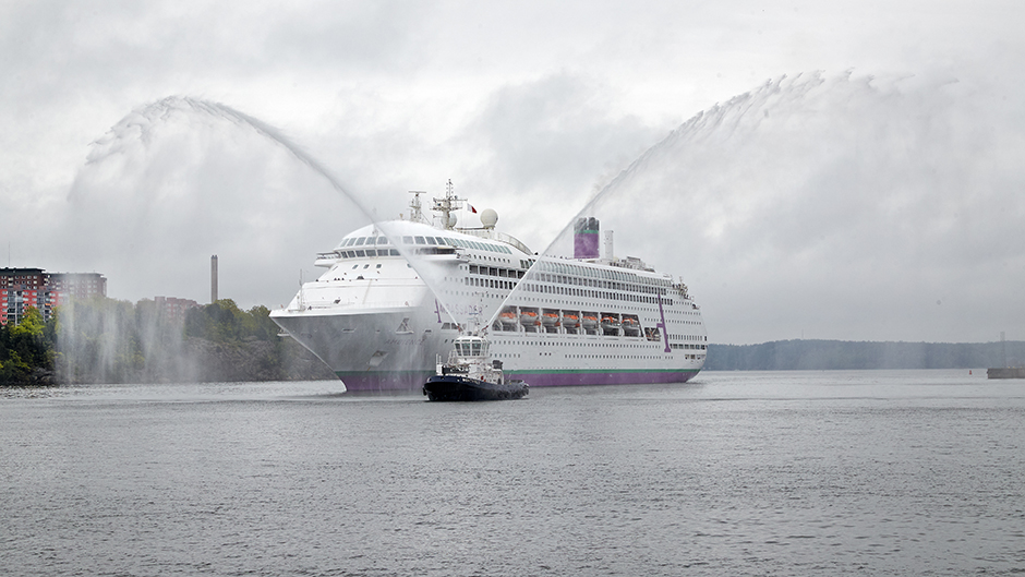 The vessel Ambience is escorted into port in Stockholm by a tug doing a water salute