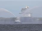 Tugboat shooting water in front of cruise vessel arriving at Port of Stockholm