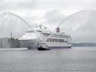 The vessel Ambience is escorted into port in Stockholm by a tug doing a water salute